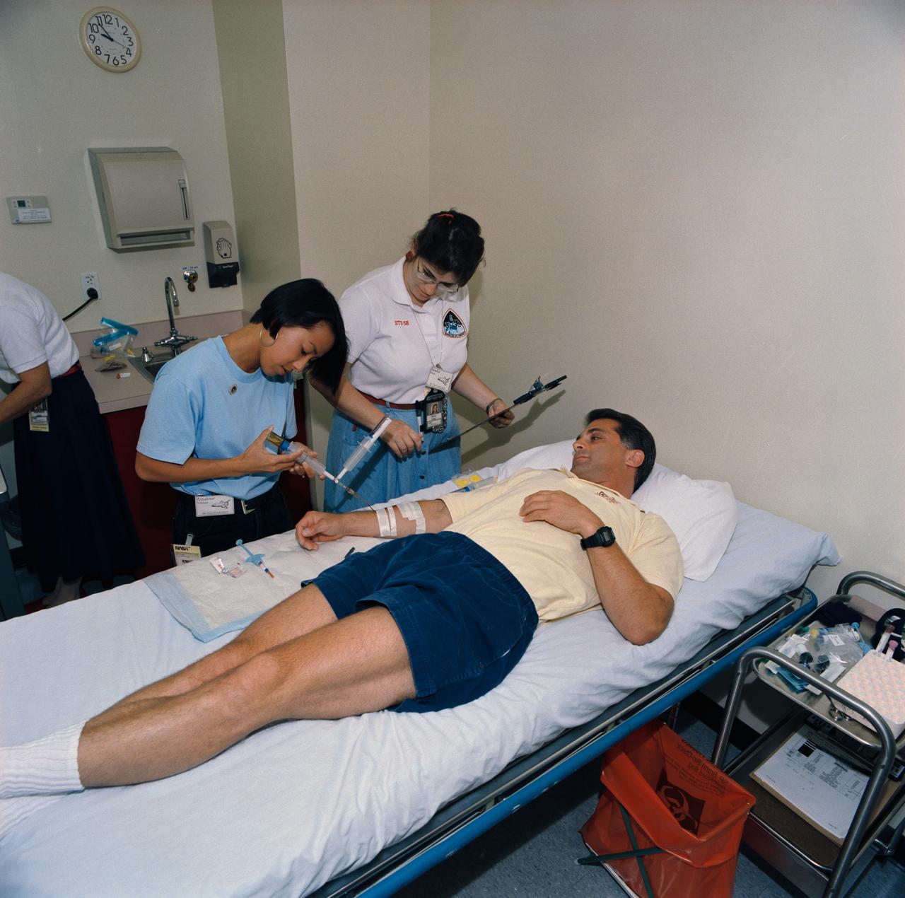 S93-45370 (29 Sept 1993) --- Blood samples from crew members are critical to several Spacelab Life Sciences (SLS-2) investigations.  Amalour Veloso (left) and Sandra Prow draw blood from David A. Wolf, mission specialist.  Wolf was participating with five other NASA astronauts and a payload specialist on data collection and training in preparation for the two week SLS-2 mission.