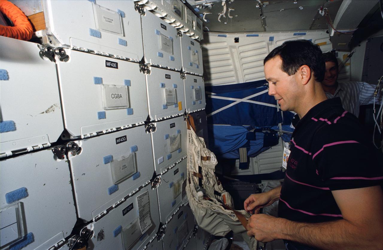 S93-46017 (13 October 1993) --- In the Johnson Space Center's (JSC) Shuttle mockup and integration laboratory, astronaut Pierre J. Thuot retrieves gear to rehearse a suit donning exercise on the middeck.  Thuot's very realistic environs are provided by the Shuttle crew compartment trainer.  Thuot, mission specialist, and four other NASA astronauts will spend two weeks in space aboard the Columbia in March of next year.  He and astronaut Andrew M. Allen have been rehearsing contingency space walks.  There is no scheduled extravehicular activity for the STS-62 flight.