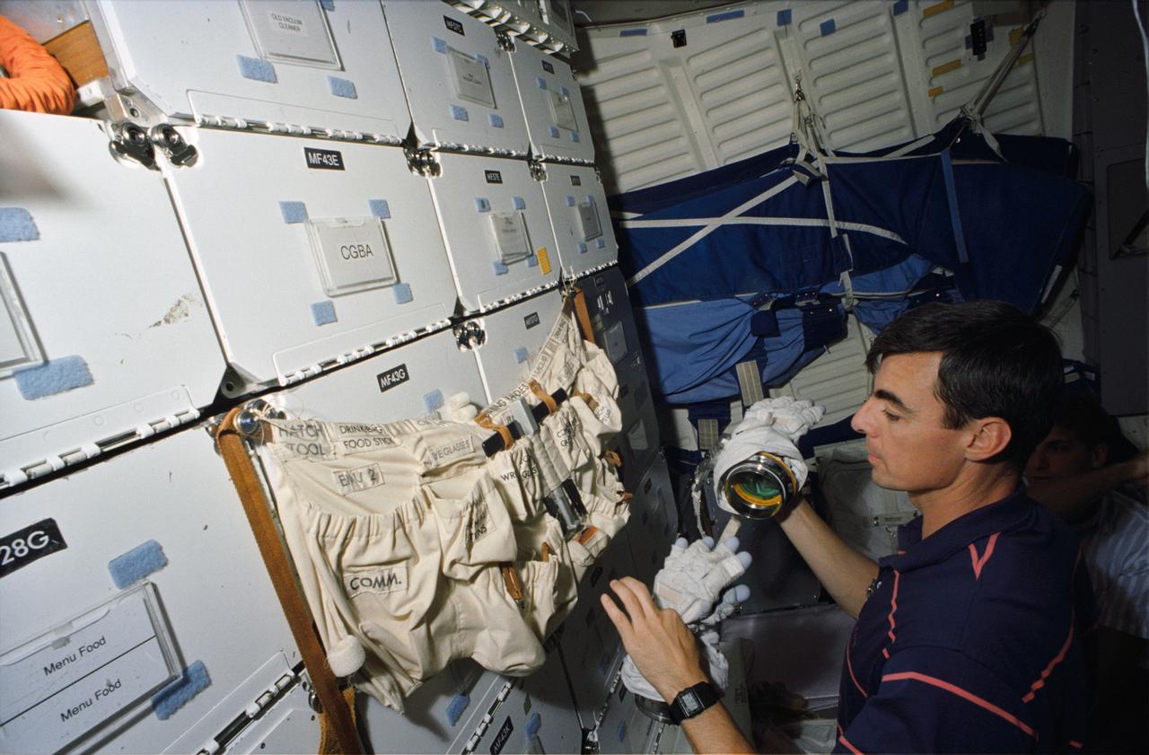 S93-46018 (13 October 1993) --- In the Johnson Space Center's (JSC) Shuttle mockup and integration laboratory, astronaut Andrew M. Allen retrieves gear to rehearse a suit donning exercise on the middeck. Thuot's very realistic environs are provided by the Shuttle crew compartment trainer. Thuot, mission specialist, and four other NASA astronauts will spend two weeks in space aboard the Columbia in March of next year. He and astronaut Pierre J. Thuot have been rehearsing contingency space walks. There is no scheduled extravehicular activity for the STS-62 flight.