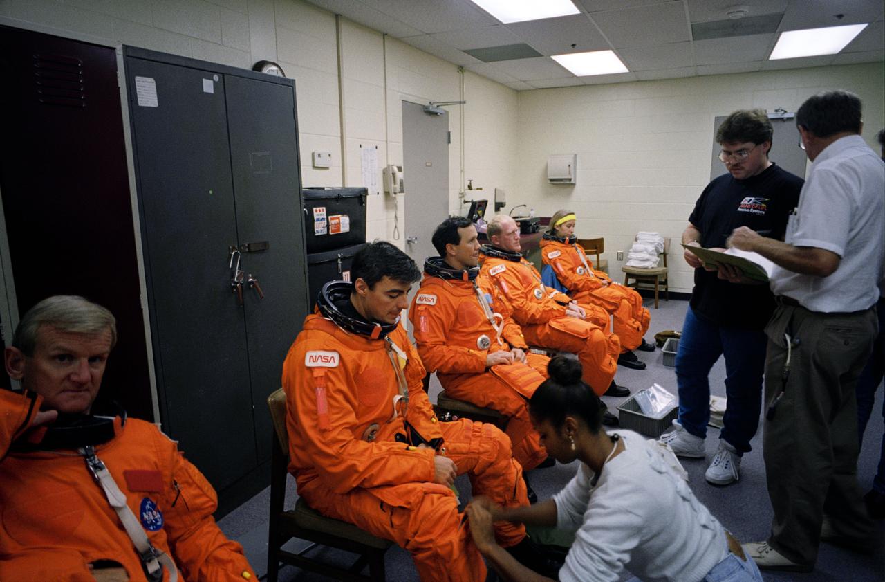 S93-48458 (5 Nov. 1993) --- In the Johnson Space Center's (JSC) Shuttle mockup and integration laboratory, the five crew members training for NASA's next mission are assisted in donning their partial pressure launch and entry suits.  From left to right are astronaut John H. Casper, Andrew M. Allen, Pierre J. Thuot, Charles D. (Sam) Gemar and Marsha S. Ivins.  Minutes later the crew was in the crew compartment trainer (CCT) rehearsing their scheduled March 1994 mission aboard the Space Shuttle Columbia.  Launch, landing and emergency egress procedures were covered in the training session.