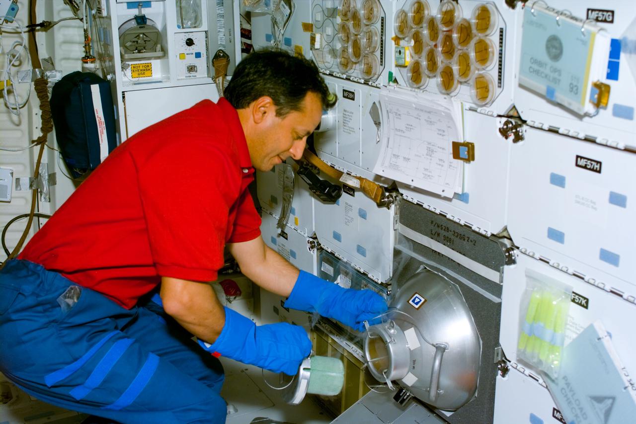S93-E-5006 (23 July 1999) --- Astronaut Michel Tognini, mission specialist representing the French space agency (CNES), opens the gaseous nitorgen (GN2) freezer on Columbia's middeck.  The  freezer is flown in support of two plant growth experiments--Plant Growth Investigations in Microgravity (PGIM) and Biological Research in Canisters (BRIC). Throughout the mission Tognini periodically freezes samples from the experiments to provide glimpses of the plants in various stages of development.  The photo was recorded with an electronic still camera (ESC) on Flight Day 1.