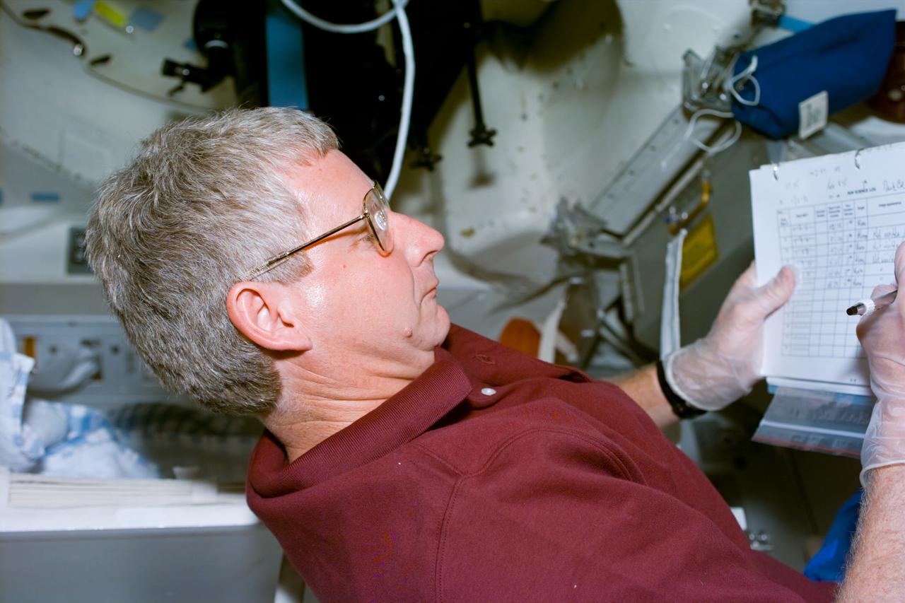 S93-E-5011 (23 July 1999) --- Astronaut Steven A. Hawley, mission specialist,  looks over a checklist on Columbia's  middeck during Flight Day 1 activity.  The image was recorded with an electronic still camera (ESC).