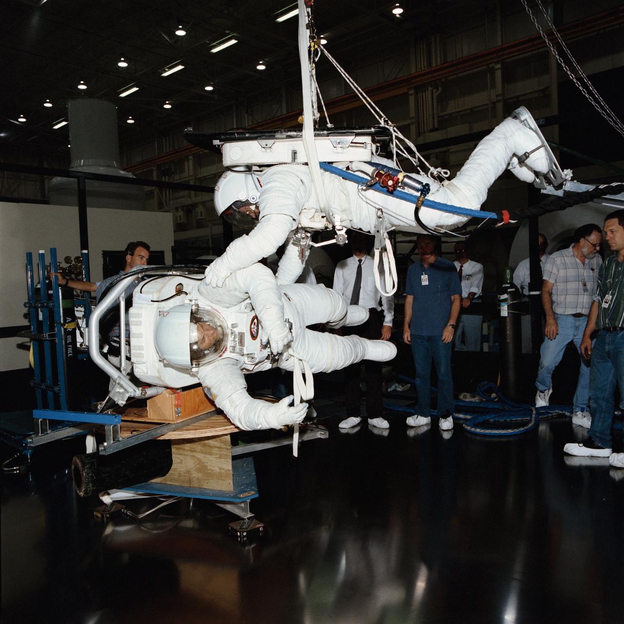 S94-33357 (1994) --- Scott Bleiseth, top, prepares to spin Mike Hess, a fellow EVA engineer, during a test on the air-bearing floor in the Shuttle Mock-up and Integration Laboratory at NASA's Johnson Space Center. The hardware being tested is part of the Simplified Aid for EVA Rescue (SAFER). The pair was developing techniques by which the non-SAFER equipped spacewalker will impart a rotation to the SAFER-using spacewalker during the STS-64 mission. Once the SAFER astronaut is spinning, the device will be activated and its automatic attitude hold capability will be tested. SAFER is to fly on STS-76 as well. Photo credit: NASA or National Aeronautics and Space Administration