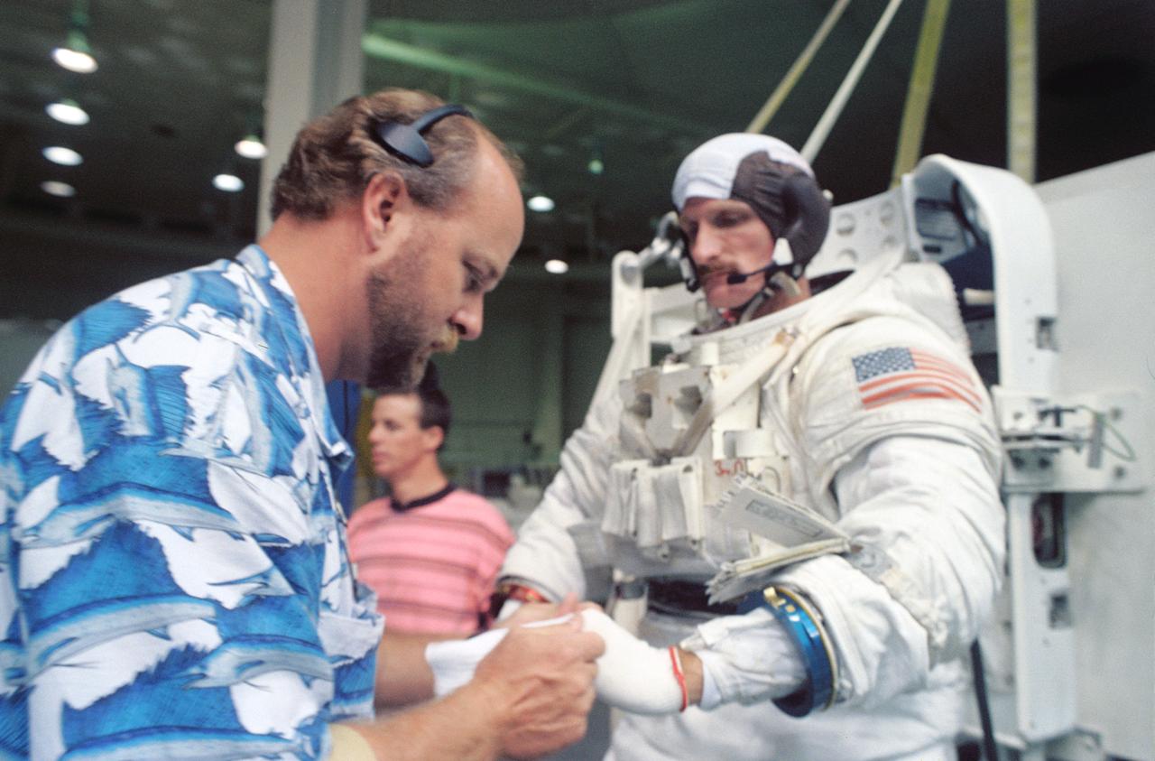 S94-40048 (1 August 1994) --- Astronaut Joseph R. Tanner, mission specialist, is assisted by Boeing suit expert Steve Voyles as he prepares to be submerged in a 25-feet deep pool at the Johnson Space Center's (JSC) Weightless Environment Training Facility (WET-F).  Though no extravehicular activity (EVA) is planned for the mission, at least two astronauts are trained to perform tasks that would require a space walk in the event of failure of remote systems.  In November, Tanner will join four other NASA astronauts and a European mission specialist for a week and a half in space aboard the Space Shuttle Atlantis.  The flight will support the Atmospheric Laboratory for Applications and Science (ATLAS-3) mission.