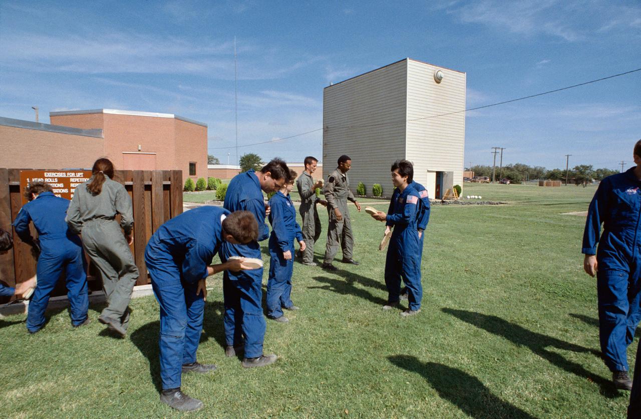 S95-00353 (12-14 September 1992) --- Several 1992 astronaut candidates brush the sand and gravel off one another following one of several phases of parachute familiarization and survival training at Vance Air Force Base in Oklahoma. Recognizable in the picture are Wendy B. Lawrence, Michael E. Lopez-Alegria, Chris A. Hadfield, Winston E. Scott and Koichi Wakata. The trainees had just completed an exercise, which required their jumping off a box into a gravel pit, in order to familiarize them the proper way to meet the ground following an emergency parachute drop.