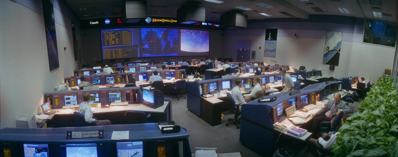 S95-16445 (13-22 July 1995) --- A wide angle view from the rear shows activity in the new Mission Control Center (MCC), opened for operation and dedicated during the STS-70 mission.  The Space Shuttle Discovery was just passing over Florida at the time this photo was taken (note mercator map and TV scene on screens).  The new MCC, developed at a cost of about 50 million, replaces the main-frame based, NASA-unique design of the old Mission Control with a standard workstation-based, local area network system commonly in use today.