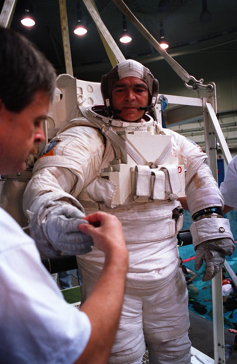 S95-21279 (September 1995) --- Astronaut Michael R. (Rich) Clifford, mission specialist, checks his gloves before being submerged in a 25-feet deep pool at the Johnson Space Center's (JSC) Weightless Environment Training Facility (WET-F).  Wearing high fidelity training versions of the Extravehicular Mobility Unit (EMU) spacesuit, both Clifford and Linda M. Godwin were later simulating Extravehicular Activity (EVA) chores in the pool.  Launch aboard the Space Shuttle Atlantis is scheduled for March of 1996.