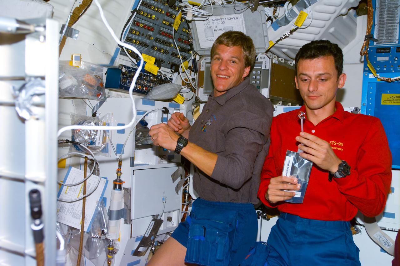 S95-E-5003 (29 Oct. 1998) --- Astronauts Scott E. Parazynski (left) and Pedro Duque, both STS-95 mission specialists, at Discovery's galley on middeck during Flight Day 1 activity. Duque represents the European Space Agency (ESA). The photo was made with electronic still camera (ESC) at 10:05:19 GMT, Oct. 29.