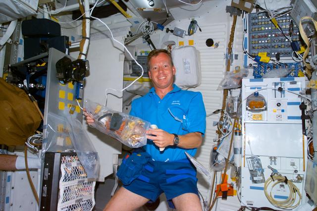 NASA image: Lindsey on middeck with bag of refuse