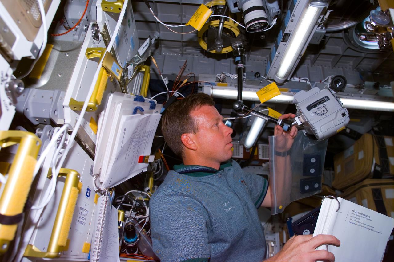 STS095-E-5107 (2 Nov. 1998) --- Astronaut Steven W. Lindsey, STS-95 pilot, sets up a camera for an experiment in the Spacehab facility aboard Discovery during Flight Day 4 activity. The photo was taken with an electronic still camera (ESC) at 05:10:25 GMT, Nov. 2.