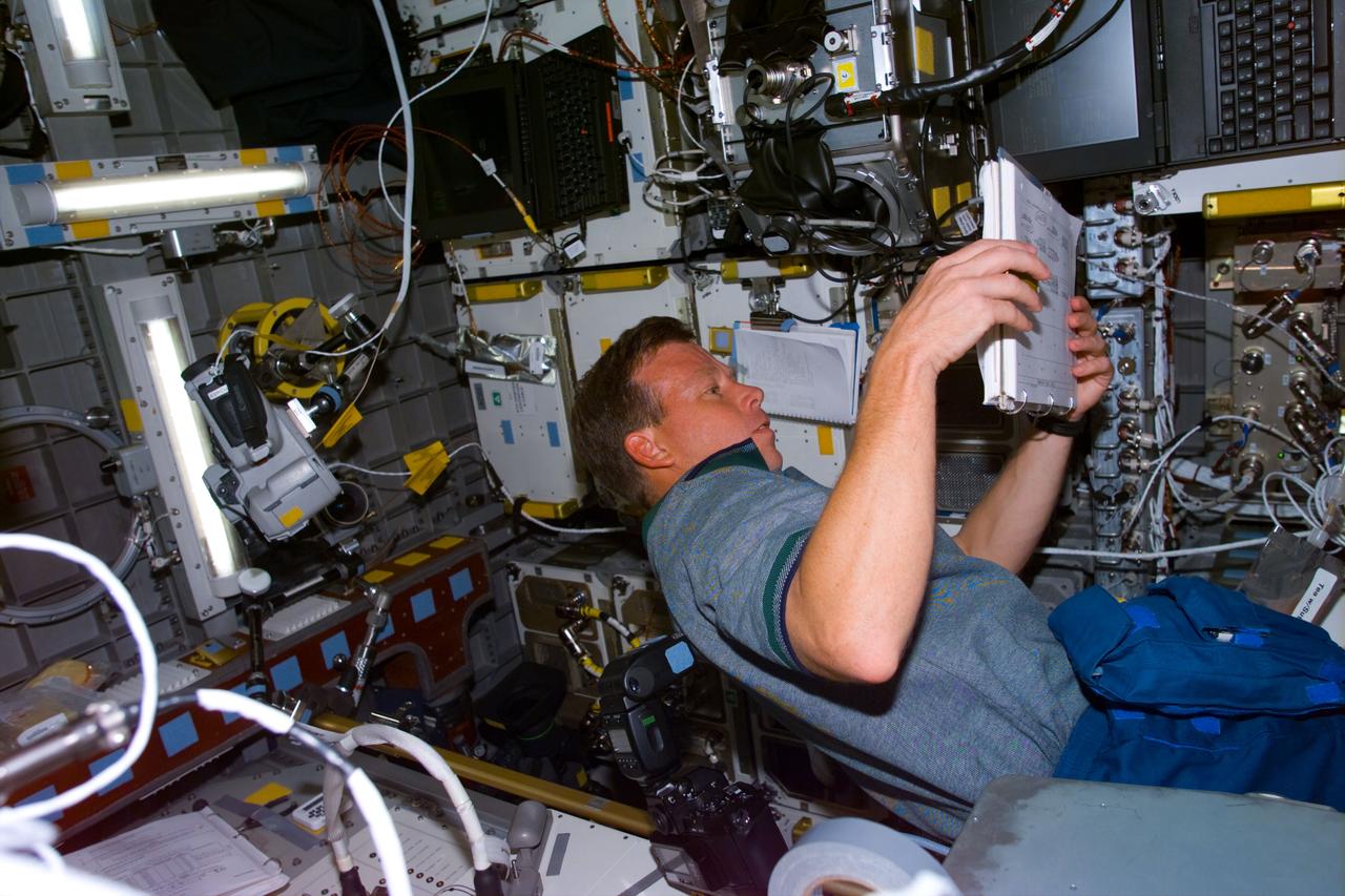 STS095-E-5120 (2 Nov. 1998) --- Astronaut Steven W. Lindsey, STS-95 pilot, checks Astroculture notes in the Spacehab facility. The glove box facility can be seen near Lindsey's head. The photo was taken with an electronic still camera (ESC) at 05:18:21 GMT, Nov. 2.