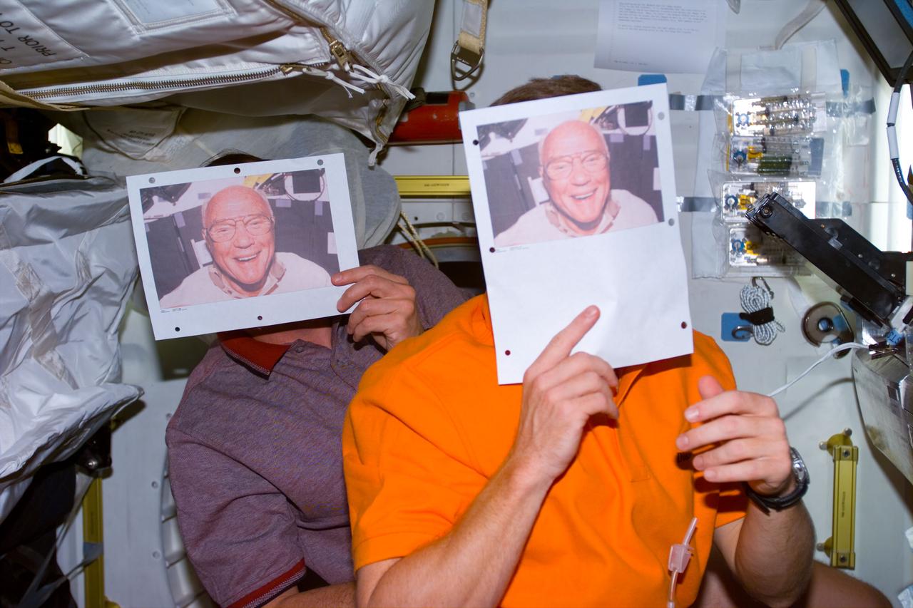 S95-E-5122 (31 Oct. 1998) -- STS-95 crew members participate in Halloween activities aboard the orbiter Discovery.  Two crew members hold up masks of U.S. Sen. John H. Glenn as their Halloween disguises on Flight Day 3. Suspicions were relatively high that the participants were astronauts Steven Lindsay and Curtis Brown, pilot and commander, respectively.  Photo credit: NASA