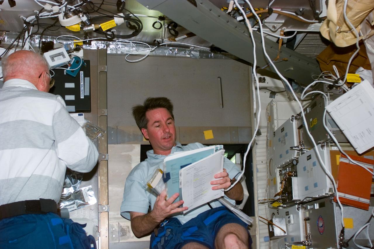 STS095-E-5151 (3 Nov. 1998) --- U.S. Sen. John H. Glenn Jr. (left), payload specialist, and astronaut Stephen K. Robinson, mission specialist, on Discovery's middeck, continue busy experimentation agenda for STS-95. The photo was taken with an electronic still camera (ESC) at 15:27:36 GMT, Nov. 3.