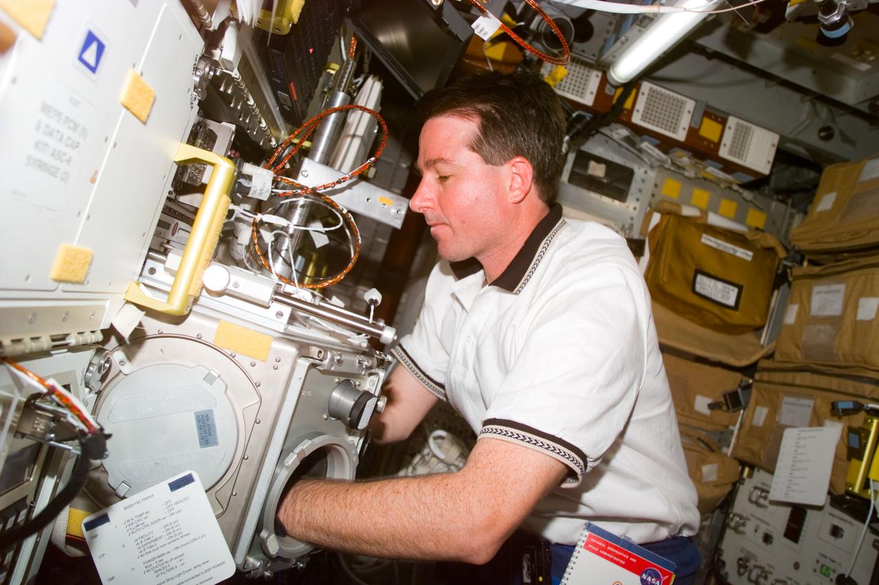 STS095-E-5163 (1 Nov. 1998) --- Astronaut Stephen K. Robinson, mission specialist, works with an experiment in the glove box located in the Spacehab facility onboard Discovery. The photo was taken with an electronic still camera (ESC) at 01:53:47 GMT, Nov. 1.