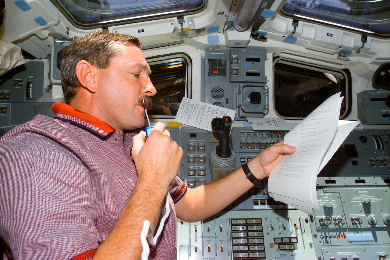 STS095-E-5177 (31 Oct. 1998) --- On Discovery's aft flight deck, astronaut Curtis L. Brown Jr., STS-95 commander, checks over notes with ground controllers in Houston. The photo was taken with an electronic still camera (ESC) at 00:41:51 GMT, Oct. 31.