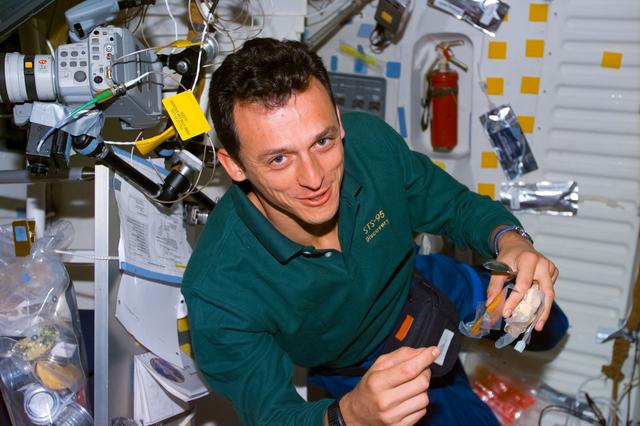 NASA image: Duque on middeck with food packets and utensils