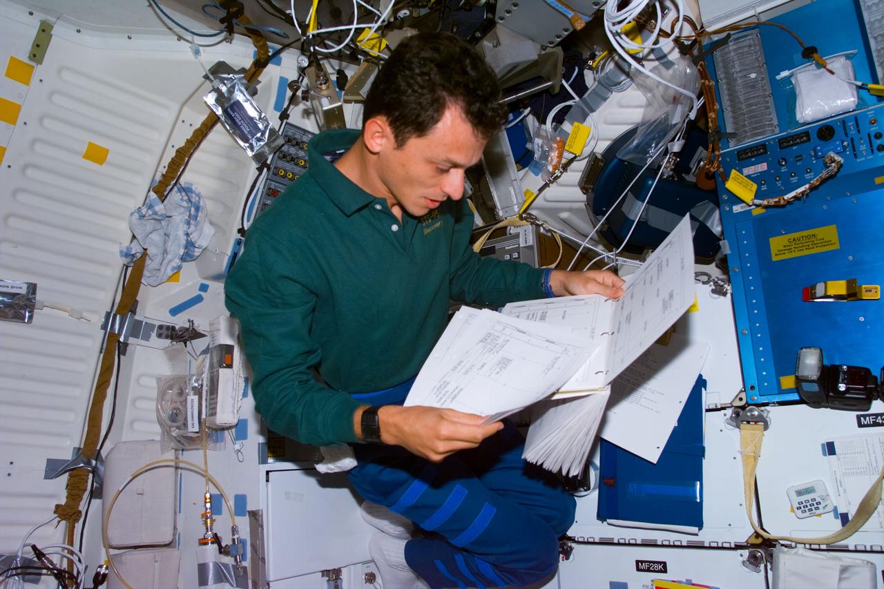 STS095-E-5237 (4 Nov. 1998) --- Astronaut Duque has his hands full of reference papers in the Spacehab facility during Flight Day 7 activity onboard the Space Shuttle Discovery.  The photo was taken with an electronic still camera (ESC) at 17:53:38 GMT, Nov. 4.