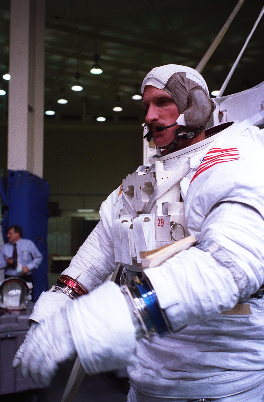 S96-12830 (10 June 1996) --- Astronaut Joseph R. Tanner, STS-82 mission specialist assigned to extravehicular activity (EVA) involved with the servicing of the Hubble Space Telescope (HST), dons the gloves for his extravehicular mobility unit (EMU) space suit.  He is about to be submerged in a 25-ft. deep pool at the Johnson Space Center's weightless environment training facility (WET-F) to participate in simulations for some of the EVA work.  Out of frame, astronaut Gregory J. Harbaugh was on the other side of the platform, waiting to join Tanner in the spacewalk rehearsal.