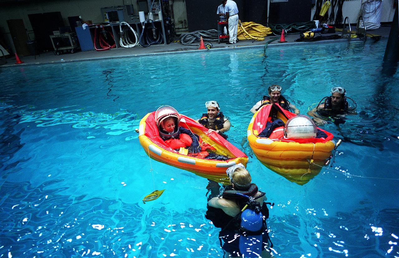 S96-15405 (26 Sept. 1996) --- In the Johnson Space Center's weightless environment training facility, astronaut Marsha S. Ivins, STS-81 mission specialist, bails water from her life raft during water bailout survival training. Astronaut Peter J.K. (Jeff) Wisoff (pictured in right raft) and four other STS-81 crewmates (out of frame) joined Ivins for the bailout training exercises. Several SCUBA-equipped divers assist in the training exercise.