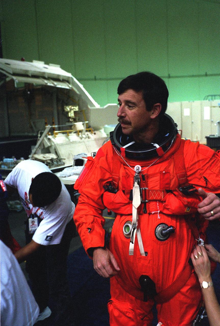 S96-18553 (30 Oct. 1996) --- Astronaut Scott J. Horowitz, pilot, gets help with his launch and entry suit prior to a training session in JSC's systems integration facility.  Wearing training versions of the partial pressure launch and entry escape suit, Horowitz and his crewmates went on to simulate an emergency ejection, using the escape pole system on the mid deck, as well as other phases of their scheduled February mission.