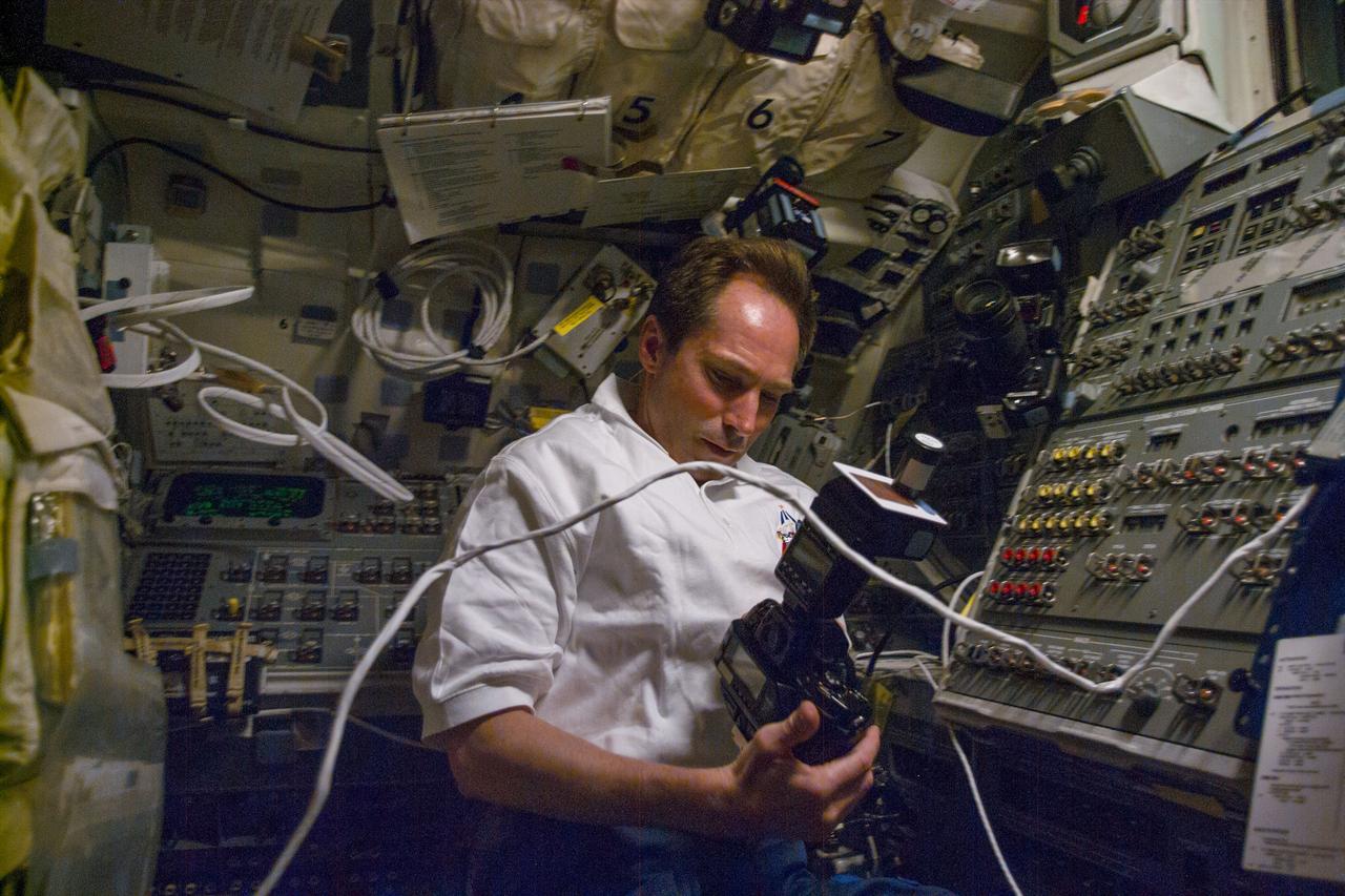 S96-E-5018 (30 May 1999) --- Cosmonaut Valery I. Tokarev, one of five mission specialists aboard Discovery, checks out a camera which is to be used later from this flight deck position to support out-the-window photography during a busy fourth day in space for STS-96.  Tokarev represents the Russian Space Agency (RSA).