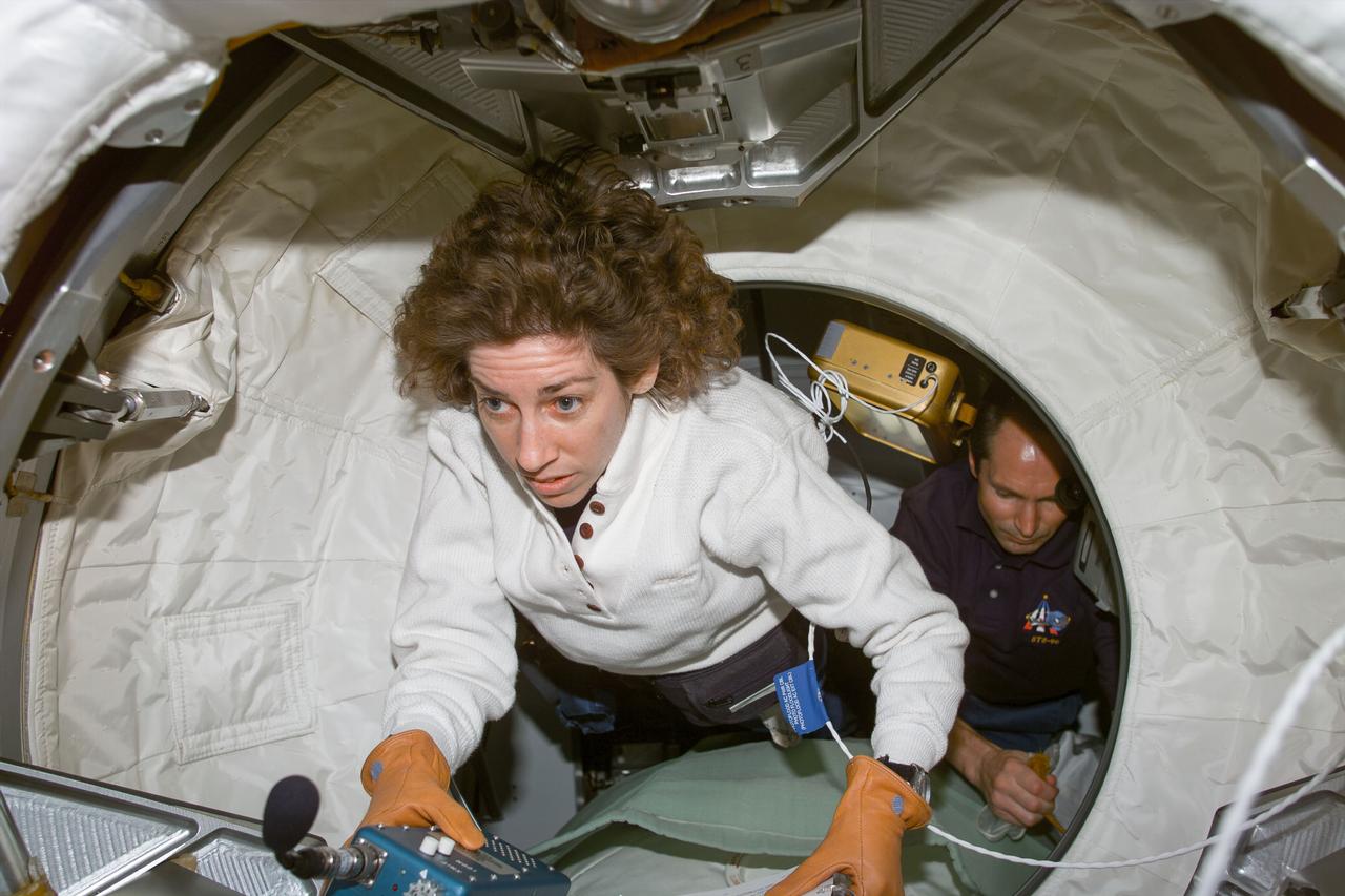 S96-E-5031 (29 May 1999) --- Astronaut Ellen Ochoa and cosmonaut Valery I. Tokarev return to the space shuttle Discovery after a brief intravehicular trip to the Pressurized Mating Adapter 2 (PMA 2) on flight day four.  The photo was recorded with an electronic still camera (ESC) at 07:02:52 GMT, May 29, 1999. Photo credit: NASA
