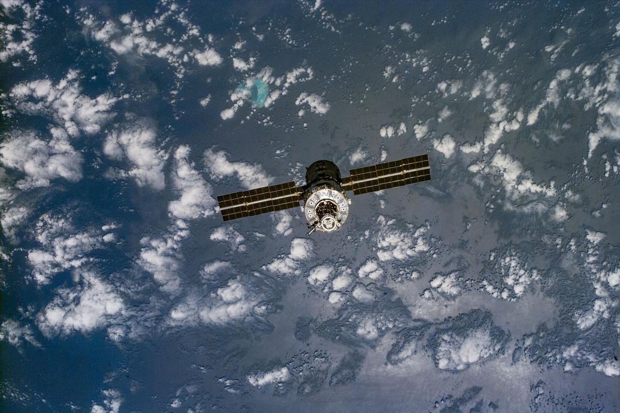 S96-E-5218 (3 June 1999) --- Partially silhouetted over clouds and a wide expanse of ocean waters, the unmanned International Space Station  (ISS) moves away from the Space Shuttle Discovery.  An electronic still camera  (ESC) was aimed through aft flight deck   windows to capture the image at 23:01:00 GMT, June 3, 1999.