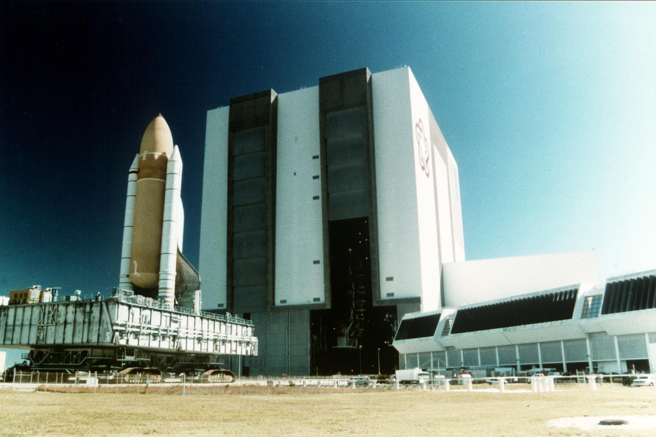 S97-00253 (10 Dec. 1996) ---- After clearing the high bay door of the Vehicle Assembly Building (VAB), the space shuttle Atlantis slowly moves out to Launch Pad 39B along the crawlerway. Atlantis is scheduled to liftoff Jan. 12 on STS-81, the first Shuttle mission of 1997. The planned nine-day flight will include the fifth Shuttle-Mir docking.