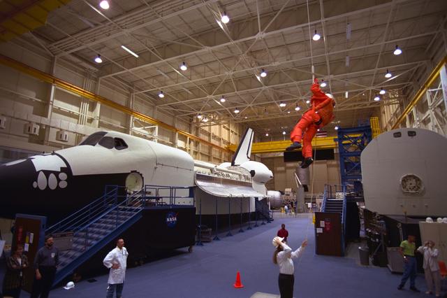 S98-06937 (28 April 1998) --- U.S. Sen. John H. Glenn Jr. (D.-Ohio), uses a device called a Sky genie to simulate rappelling from a troubled Space Shuttle during training at the Johnson Space Center (JSC). Glenn has been named as a payload specialist for STS-95, scheduled for launch later this year. This exercise, in the systems integration facility at JSC, trains the crewmembers for procedures to follow in egressing a troubled shuttle on the ground. The full fuselage trainer (FFT) is at left, with the crew compartment trainer (CCT) at right. Photo Credit:  Joe McNally, National Geographic, for NASA