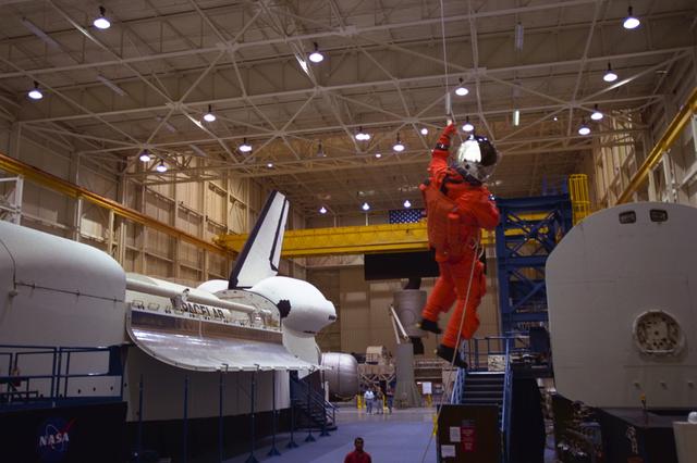 S98-06938 (28 April 1998) --- U.S. Sen. John H. Glenn Jr. (D.-Ohio), uses a device called a Sky genie to simulate rappelling from a troubled Space Shuttle during training at the Johnson Space Center (JSC). Glenn has been named as a payload specialist for STS-95, scheduled for launch later this year. This exercise, in the systems integration facility at JSC, trains the crewmembers for procedures to follow in egressing a troubled shuttle on the ground. The full fuselage trainer (FFT) is at left, with the crew compartment trainer (CCT) at right. Photo Credit:  Joe McNally, National Geographic, for NASA