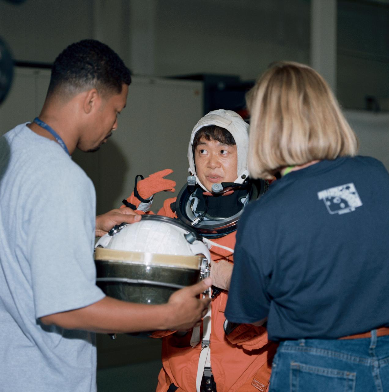Photographic documentation of the STS-95 crew emergency egress training at the bldg 9A Full Fuselage Trainer (FFT). Views include: Mission specialist Senator John Glenn (in his orange Launch and Landing (LES) suit) is photographed by his wife as other visitors look on (07958). STS-95 crewmember prepares to use the Sky Genie to climb down the side of the FFT (07959). STS-95 crew lines up to pose for pictures in their LES's. Left to right are: Mission specialist Pedro Duque, payload specialist Chiaki Mukai, commander Curt Brown, payload specialist U.S. Senator John Glenn, mission specialist Stephen Robinson, pilot Steven Lindsey, and mission specialist Scott F. Parazynski (07960). Parazynski, Glenn and Robinson talk while their photo is being taken (07961). Mukai receives assistance from suit techs in donning her LES helmet (07962). Glenn receives assistance from suit techs in donning his LES helmet (07963). Glenn, in his LES, walks toward the FFT (07964). Glenn uses the Sky Genie to prepare to climb down the side of the FFT (07965). View of Mrs. Annie Glenn watching her husband during training (07966). Mukai receives assistance from a suit tech with her LES while Glenn watches (07967). Close-up view of Mukai in her LES without a helmet (07968). Glenn and Mukai prepare to strap themselves into their seats in the mockup of the FFT middeck (07969-70). Close-up view of Mukai with her helmet on (07971). Mukai climbs down the rope with help from a technician on the ground (07972). Lindsey, Parazynski, Duque, Mukai and Glenn are photographed seated, waiting for training (07973). Close-up of Duque without his helmet (07974). Close-up of Lindsey with his helmet on, talking to a trainer (07975-6). View of Lindsey climbing down the rope (07977).