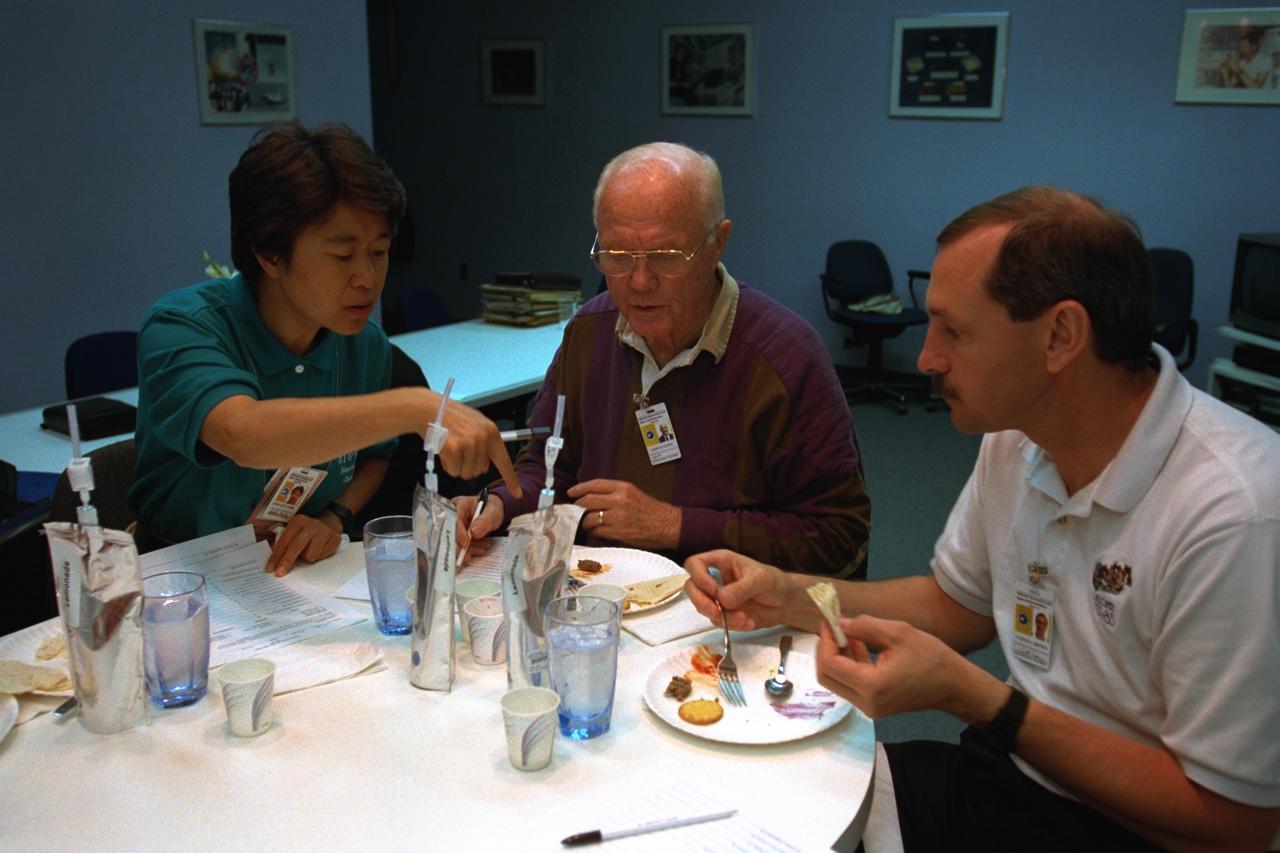 S98-08737 (9 April 1998) --- The mission commander, along with two payload specialists in training for NASA's STS-95 mission scheduled for later this year aboard Discovery, samples space foods at the Johnson Space Center (JSC). With payload specialists Chiaki Mukai and U.S. Sen. John H. Glenn Jr. (D.-Ohio) is Curtis L. Brown Jr. (right), mission commander. The photo was taken by Joe McNally, National Geographic, for NASA.