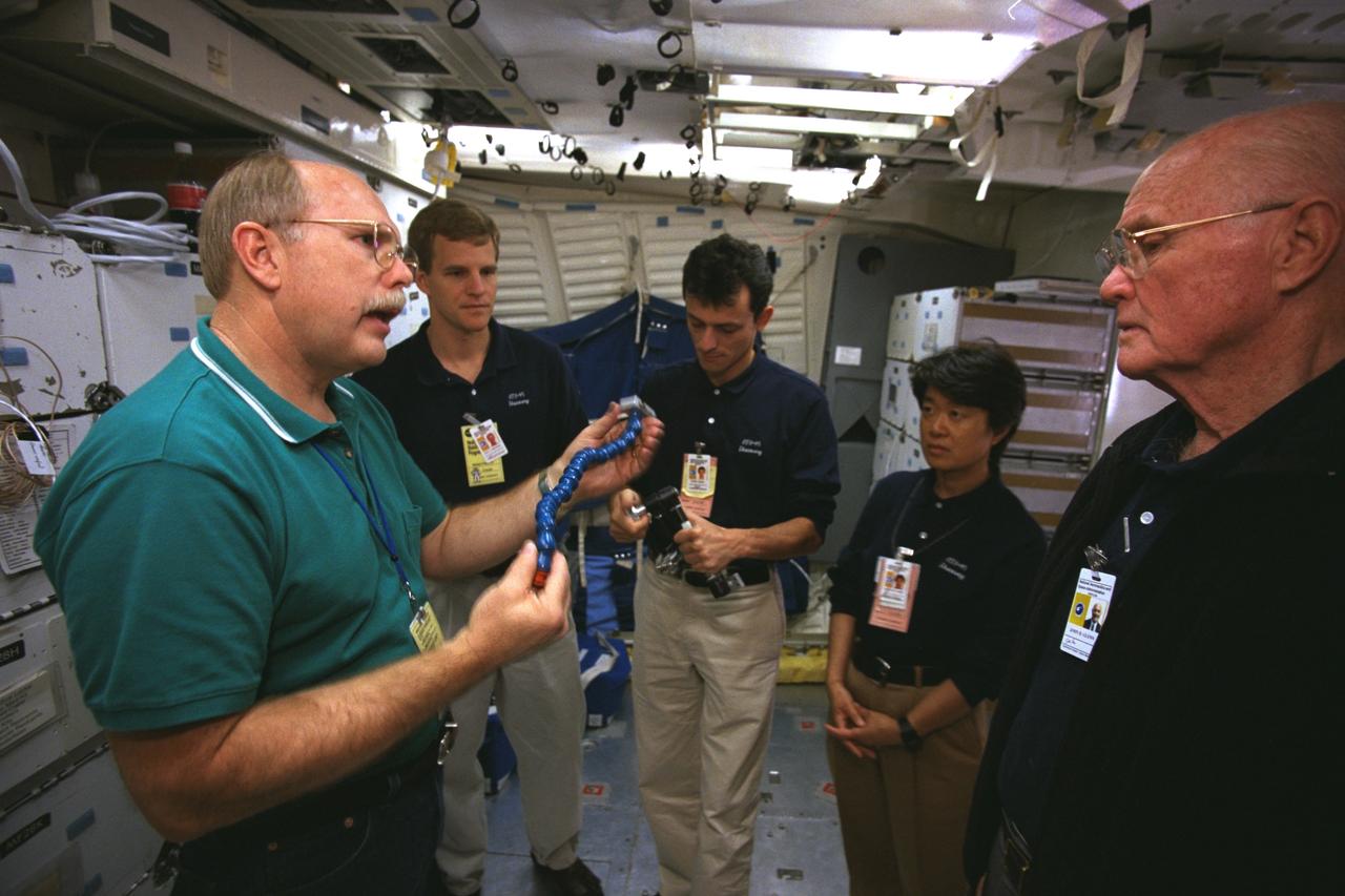 S98-08745 (May 1998) --- Four members of the STS-95 crew are briefed on flight hardware during a training session in the shuttle crew compartment trainer (CCT) at the Johnson Space Center (JSC). Donald C. Carico, an instructor, holds a loc-line bracket. Crewmembers, from the left, are Scott E. Parazynski and Pedro Duque, both mission specialists; Chiaki Mukai and U.S. Sen. John H. Glenn Jr., both payload specialists.  Duque represents the European Space Agency (ESA) and Mukai, Japan's National Space Development Agency (NASDA). The photo was taken by Joe McNally, National Geographic, for NASA.