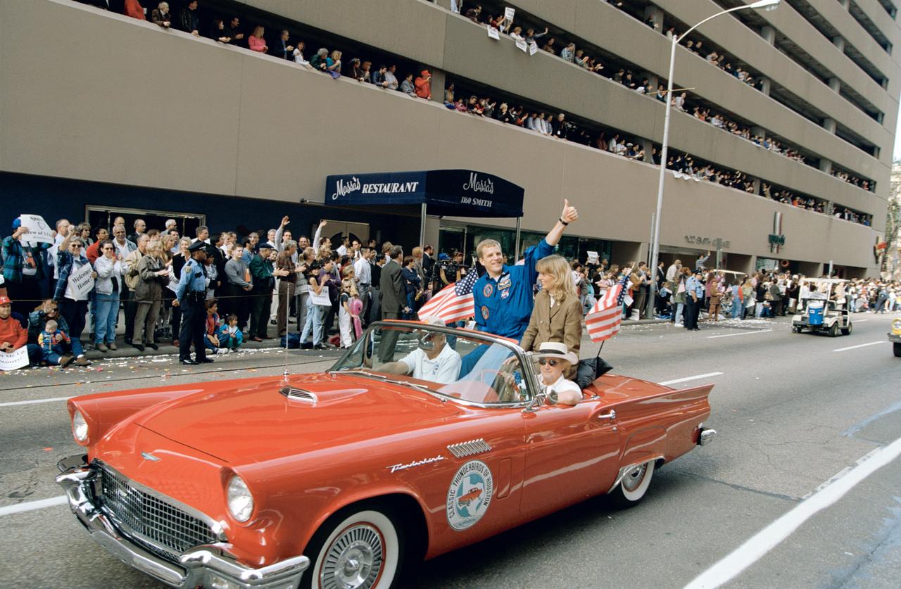 Downtown Houston parade honoring STS-95 crew. View is of Astronaut Scott Parazynski and family in car being greeted by crowd.