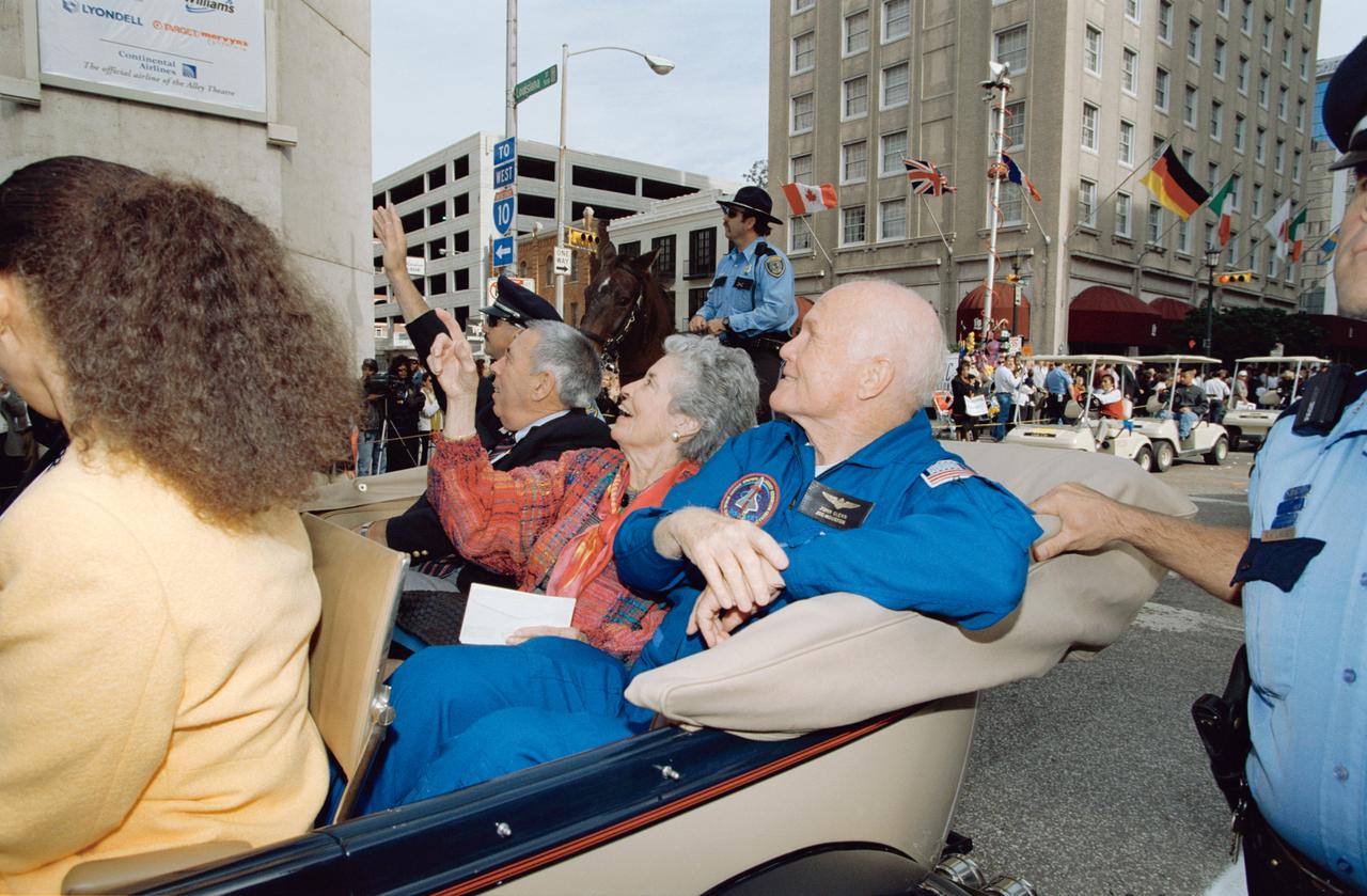 Downtown Houston parade honoring John Glenn and STS-95 crew.View is of Glenn and family in car being greeted by the crowd.