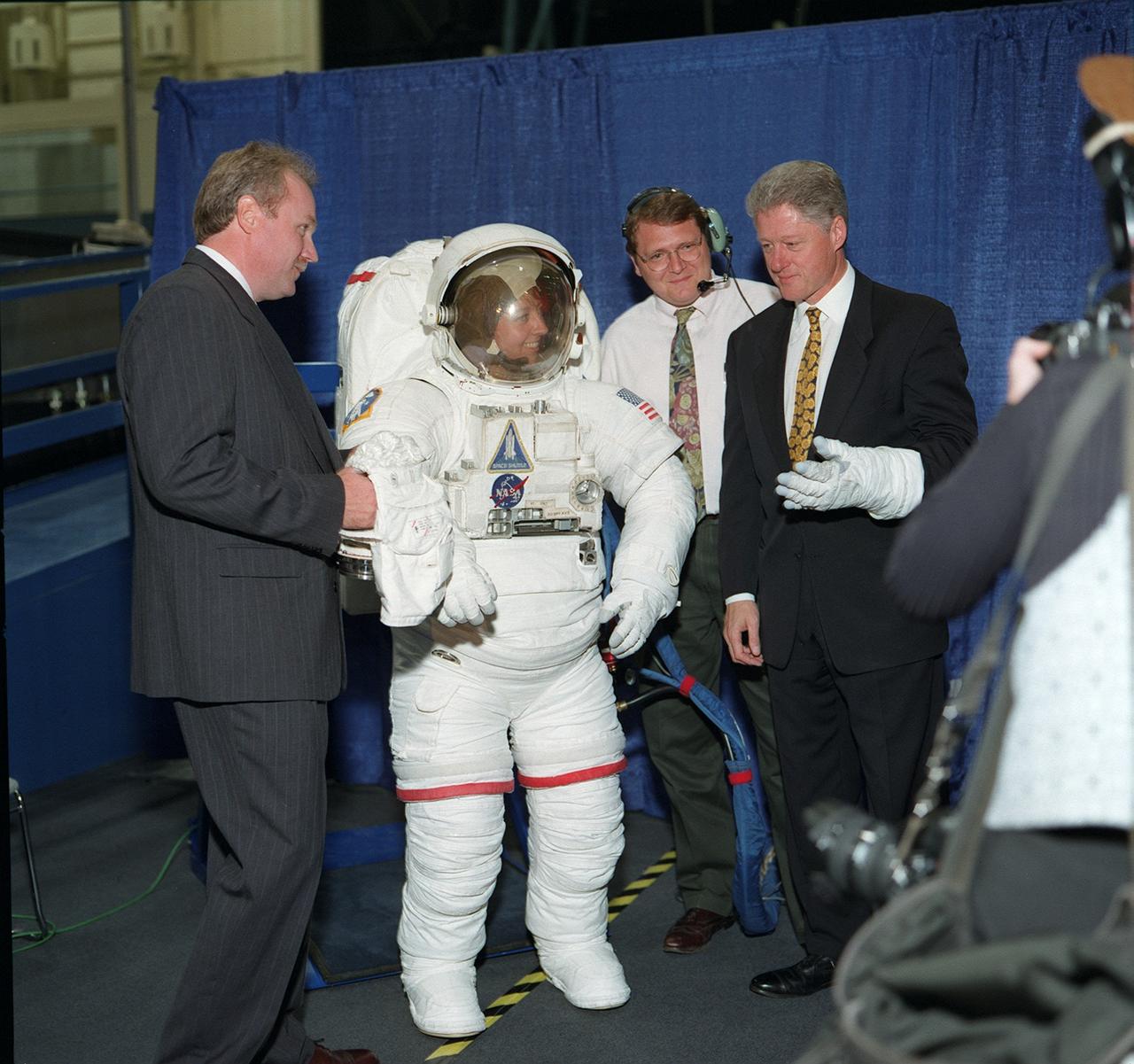 S98-05013 (14 April 1998) --- President Bill Clinton tries on a glove from the Space Shuttle extravehicular mobility unit (EMU) space suit during an April 14 visit to the Johnson Space Center (JSC). In the suit is Amy Ross, a JSC engineer. Others pictured are William E. (Bill) Spenny (left) of the EVA and Spacesuit Systems Branch in the Crew and Thermal Systems Division, Engineering Directorate; and Stephen N. Anderson (second right) of ILC. Photo Credit:  NASA or the National Aeronautics and Space Administration