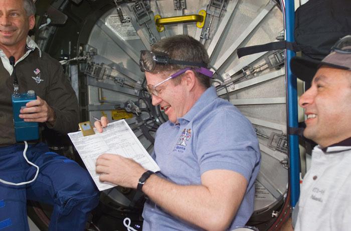 STS98-E-5129 (11 February 2001) --- Inside the Unity node, astronaut William M. (Bill) Shepherd (center), Expedition One commander, signs a document of receipt of the U.S. laboratory, called Destiny, as part of the International Space Station (ISS).  Looking on are astronauts Kenneth D. Cockrell (left) and Mark L. Polansky, commander and pilot, respectively, for STS-98. The hatch to Destiny, not yet opened, is in the background. This scene was recorded with a digital still camera.