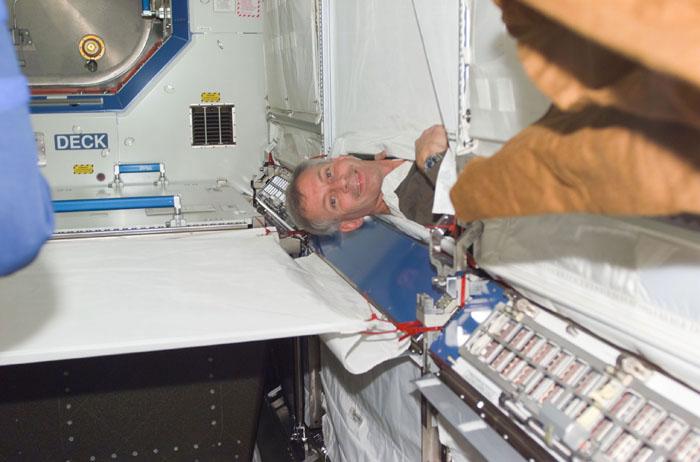 STS98-E-5149 (11 February 2001) ---  Astronaut Kenneth D. Cockrell, STS-98 commander, emerges from behind temporary  covering in the newly attached Destiny  laboratory onboard the International Space Station (ISS).  After the Destiny hatch was opened early in the day, members of both crews went to work quickly inside the new module, activating air systems, fire extinguishers, alarm systems, computers and internal communications. The crews also took some photos and continued equipment transfers from the shuttle to the station. The scene was taken with a digital still camera.