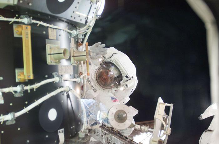 STS98-E-5190 (12 February 2001) --- Astronaut Robert L. Curbeam, STS-98 mission specialist, waves to a crew mate inside the Space Shuttle Atlantis' crew cabin from his position near Pressurized Mating Adapter (PMA-3) during the second of three scheduled space walks on 5a. The scene was recorded with a digital still camera.