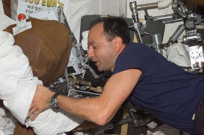 STS98-E-5220 (14 February 2001) --- Astronaut Mark L. Polansky, pilot, assists one of the STS-98 space walkers with his boot during suit donning aboard the Space Shuttle Atlantis. The scene was recorded with a digital still camera.