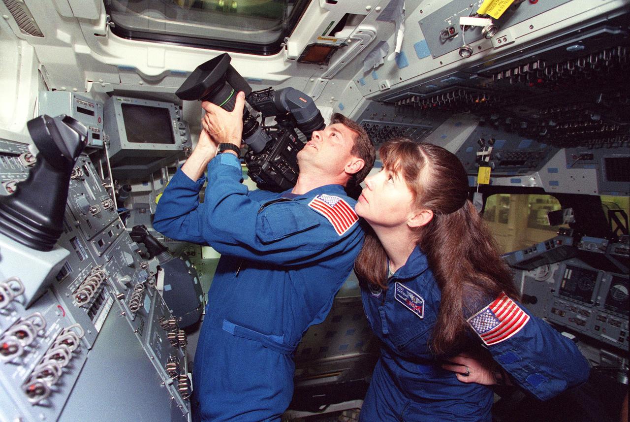 S99-05085 (April 1999) --- In preparation for a STS-93 detailed test objective (DTO), astronauts Jeffrey S. Ashby, pilot, and Catherine G. (Cady) Coleman, mission specialist, train with a high-definition television camcorder. The camera will be carried onboard the Space Shuttle Columbia for their scheduled July mission. The rehearsal with the DTO 700-17A hardware took place in the Crew Compartment Trainer (CCT)in the Systems Integration Facility at the Johnson Space Center (JSC).