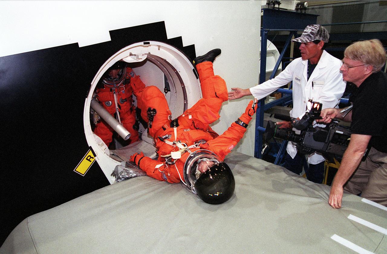 S99-05615 (19 May 1999) --- Astronaut Gerhard P.J. Thiele, mission specialist representing the European Space Agency (ESA), slides off the shuttle escape pole onto a soft surface during emergency bailout training for the STS-99 crew members. A second STS-99 crew member awaits his turn.  Looking on are technician David Borjas (second right) and videographer Charles Clendaniel (right). The training took place at the crew compartment trainer (CCT) in the Systems Integration Facility at the Johnson Space Center (JSC).
