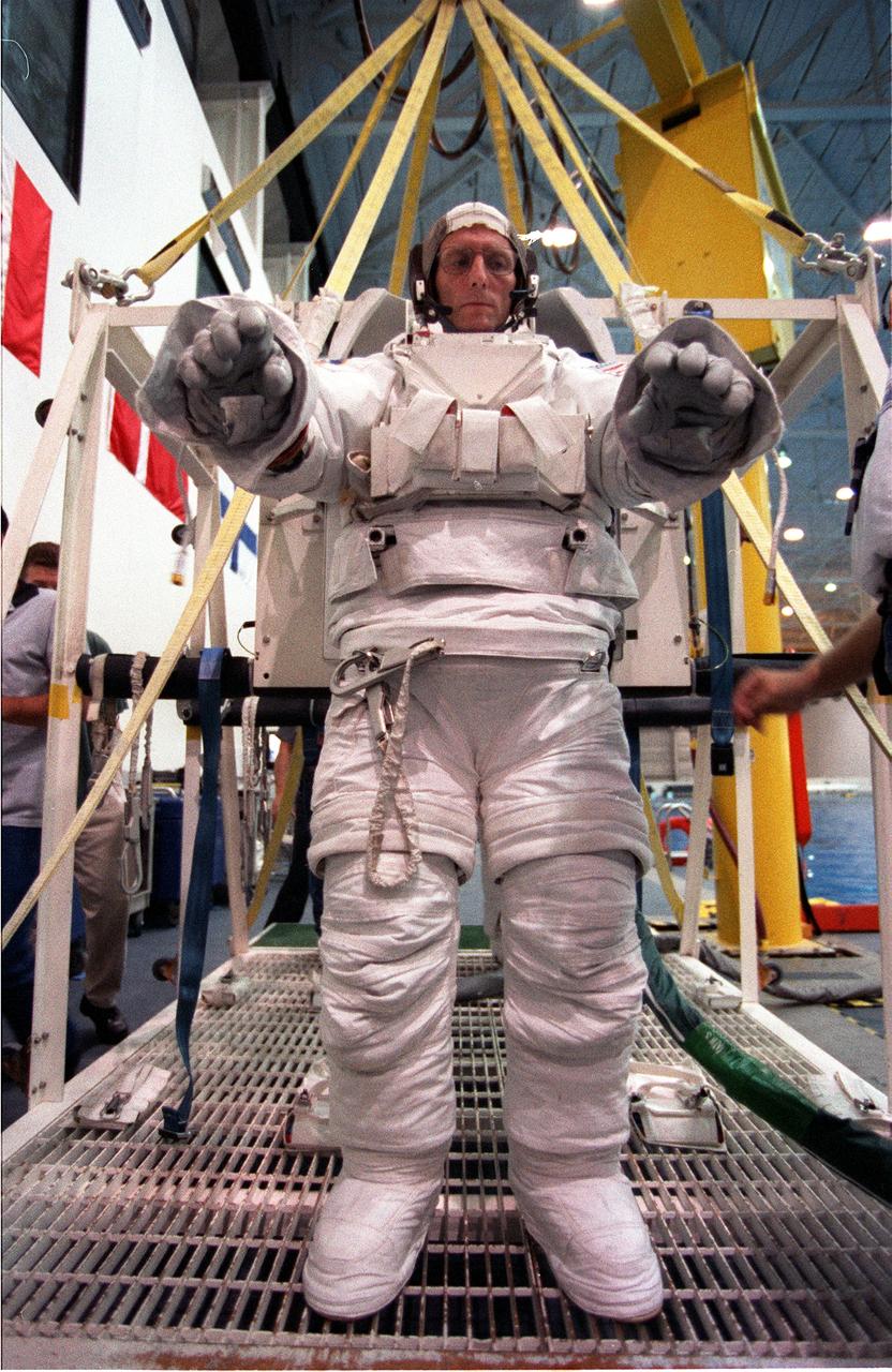 S99-05721 (26 May 1999) --- Astronaut Gerhard P.J. Thiele, mission specialist representing the European Space Agency (ESA), awaits his helment as he stands on a movable platform.  Minutes later, he and astronaut Janet L. Kavandi (not visible behind Thiele)were lowered into the nearby pool for an underwater training session at the Johnson Space Center's Neutral Buoyancy Laboratory (NBL), part of the Sonny Carter Training Center.  Thiele and Kavandi have weights on the training version of their extravehicular mobility units (EMU) which help to provide neutral buoyancy in the deep pool. The astronauts were participating in a rehearsal of a contingency space walk.