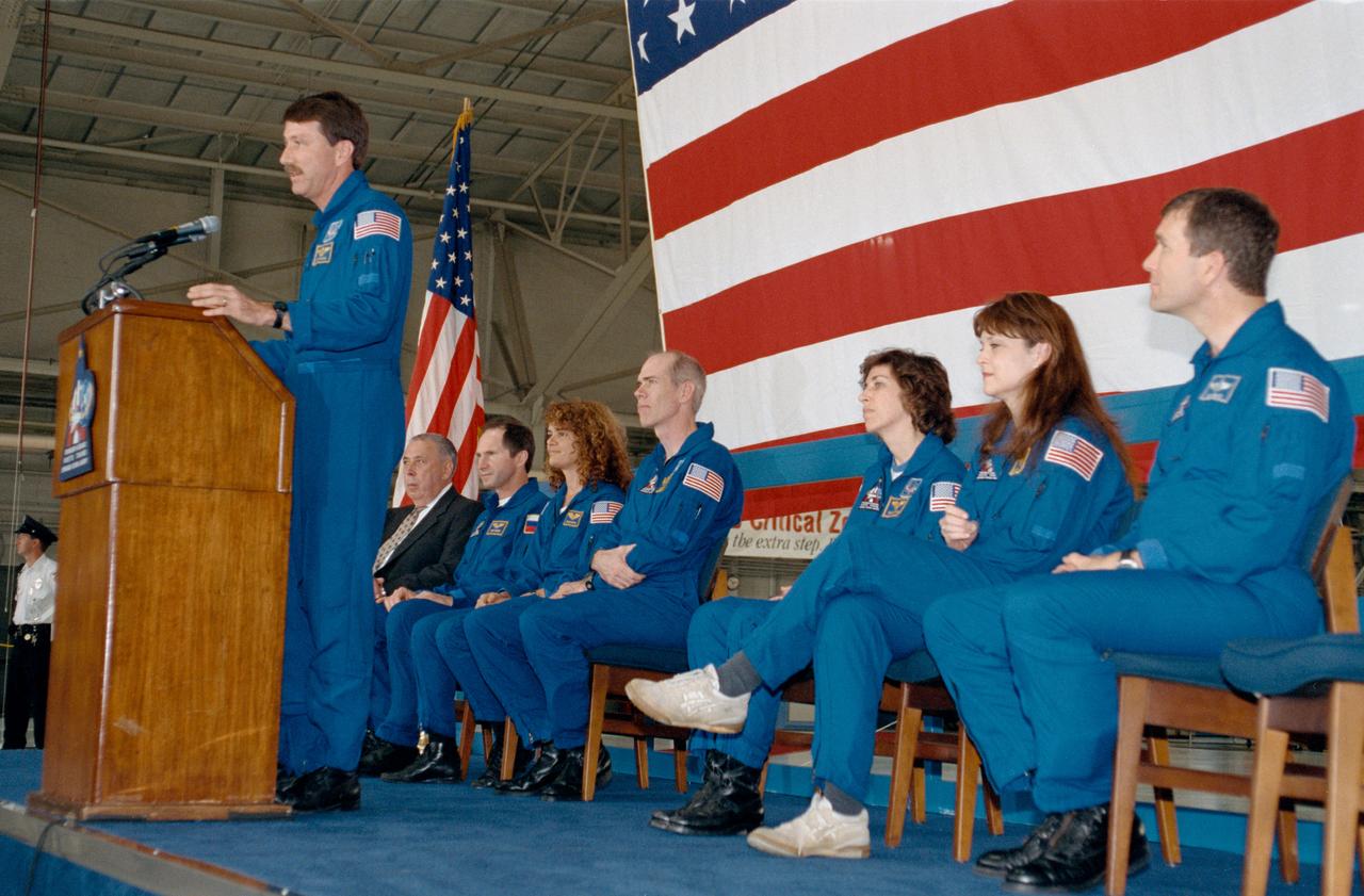 S99-05968 (7 June 1999) --- Astronaut  Kent V. Rominger, mission commander,  speaks to crowd on hand at Ellington Field's Hangar 990 following crew arrival.  In the background, from the left, are JSC Director George W.S. Abbey and cosmonaut Valeriy I. Tokarev along with astronauts Julie Payette, Daniel T. Barry, Ellen Ocoa and Tamara E. Jernigan, all mission specialists; and Rick D. Husband, pilot. Tokarev represents the Russian Space Agency (RSA) and Payette, the Canadian Space Agency (CSA).