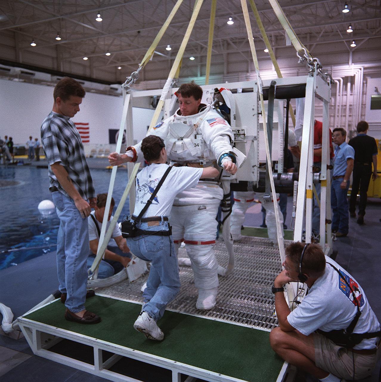 S99-06192 (21 June 1999) --- Astronaut C. Michael Foale, mission specialist, wearing an underwater-adapted training version of the Shuttle extravehicular mobility unit (EMU), prepares to go below the water in the Neutral Buoyancy Laboratory (NBL). Foale and other astronauts assigned to STS-103 space walk duty are in training for EVA chores they will handle when they make the third servicing visit to the Earth-orbiting Hubble Space Telescope (HST) since its deployment in April 1990.