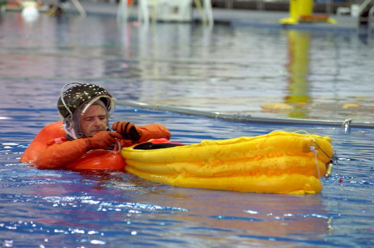S99-07008 (9 July 1999) --- Astronaut Marc Garneau, mission specialist representing the Canadian Space Agency, puts the final touches on the life raft he's just deployed during a simulated emergency bailout exercise in the Neutral Buoyancy Laboratory at the Sonny Carter Training Center.
