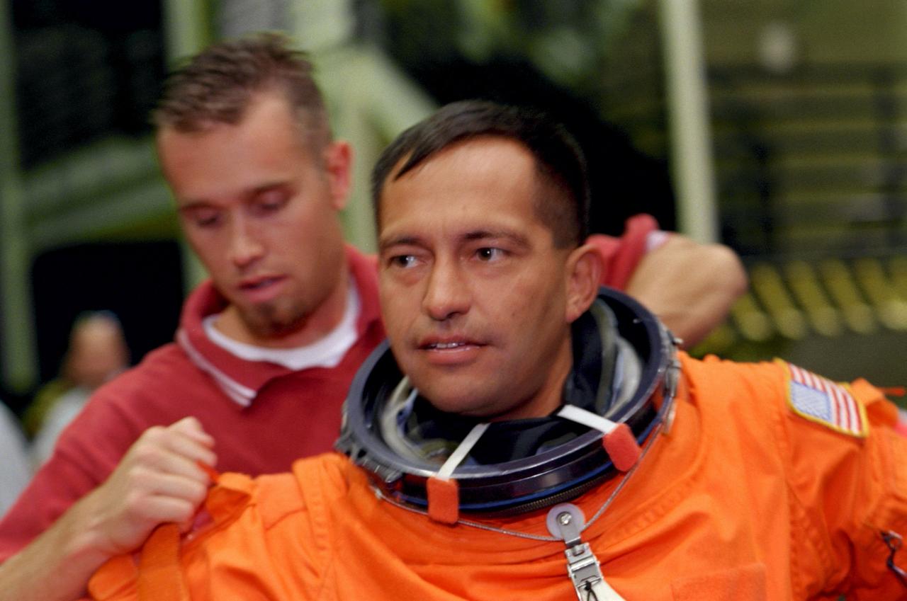 S99-07621 (15 July 1999) --- Astronaut Marc Garneau, mission specialist representing the Canadian Space Agency, requires the assistance of two suit technicians as he dons his full pressure, launch and entry garment prior to a training session at the Johnson Space Center's Systems Integration Facility.