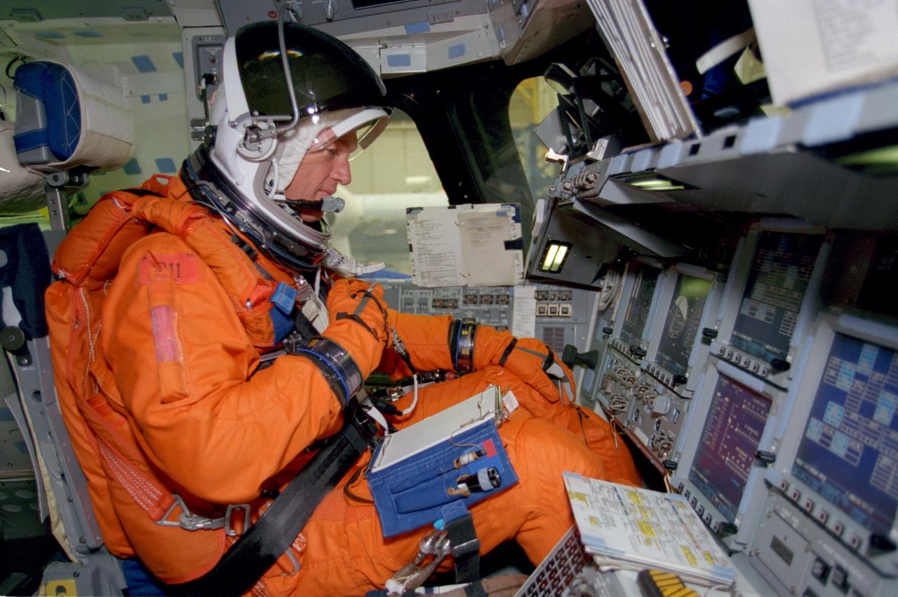 S99-07639 (15 July 1999) --- Astronaut Brent W. Jett, Jr., STS-97 mission commander, goes over a checklist while seated at the commander's station of a trainer/mockup during a dry-run of launch countdown procedures.
