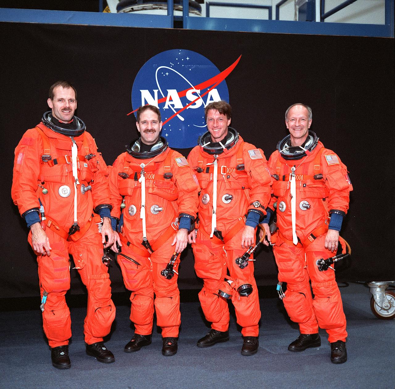 S99-08655 (24 May 1999) --- From the left, astronauts Steven L. Smith, John M. Grunsfeld, C. Michael Foale and Claude Nicollier, all mission specialists, pose for an informal portrait. The STS-103 crew members are wearing training versions of the shuttle partial-pressure launch and entry space garments. Nicollier is one of two astronauts on this flight who represents the European Space Agency (ESA).