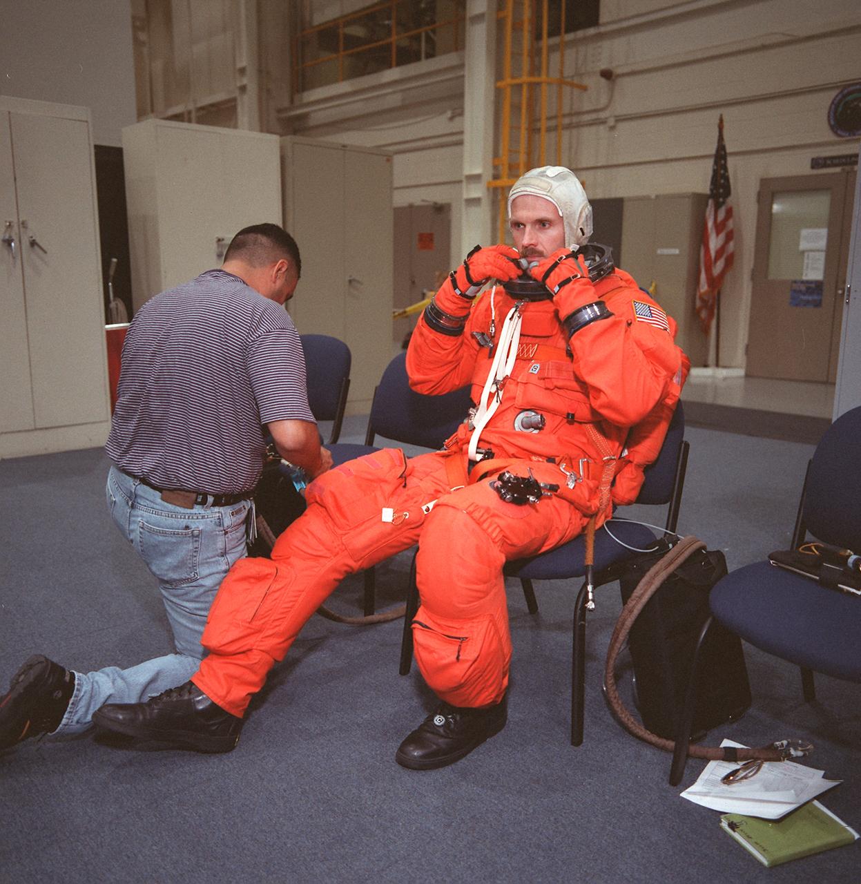 S99-08665 (24 May 1999) --- A suit technician assists astronaut Steven L. Smith with his launch and entry suit prior to an emergency bailout training session at the Johnson Space Center's Systems Integration Facility. The STS-103 mission specialists was joined on this session by the majority of the seven-man crew, in training for the third servicing mission to the Earth-orbiting Hubble Space Telescope (HST).